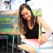 Smiling student painting on a canvas