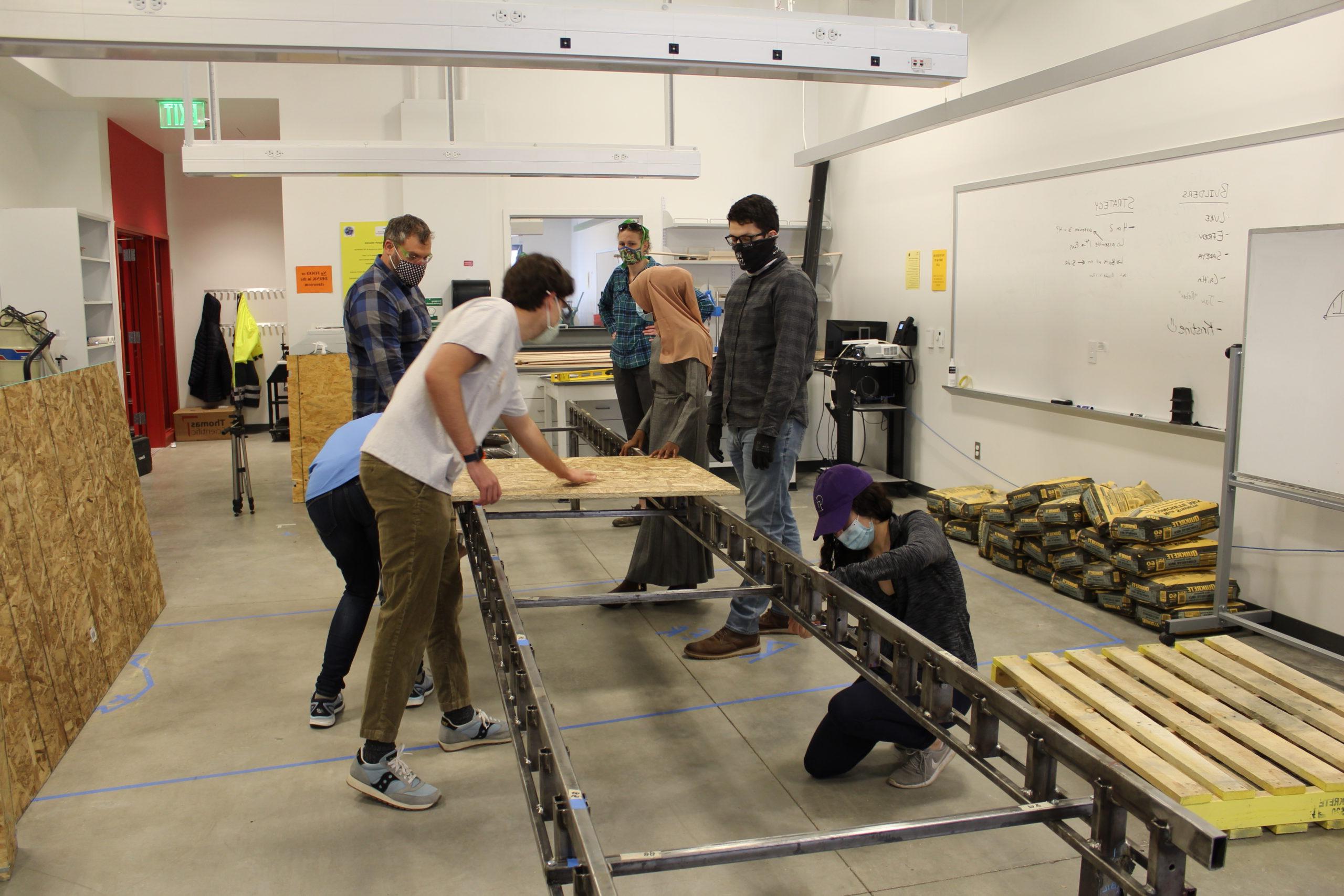 Individuals in mask working on a large metal structure