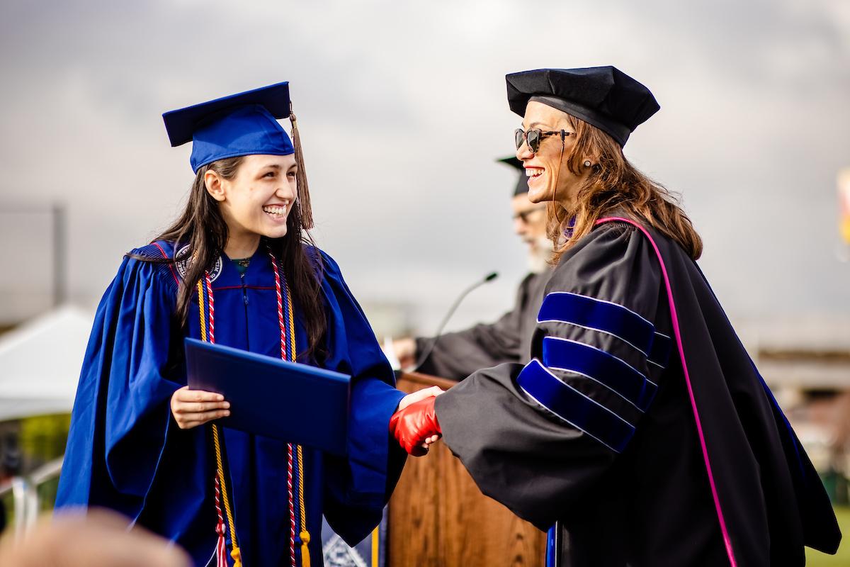 President of MSU Denver, Dr. Davidson, Ph.D. is shaking hands with a MSU Denver graduate