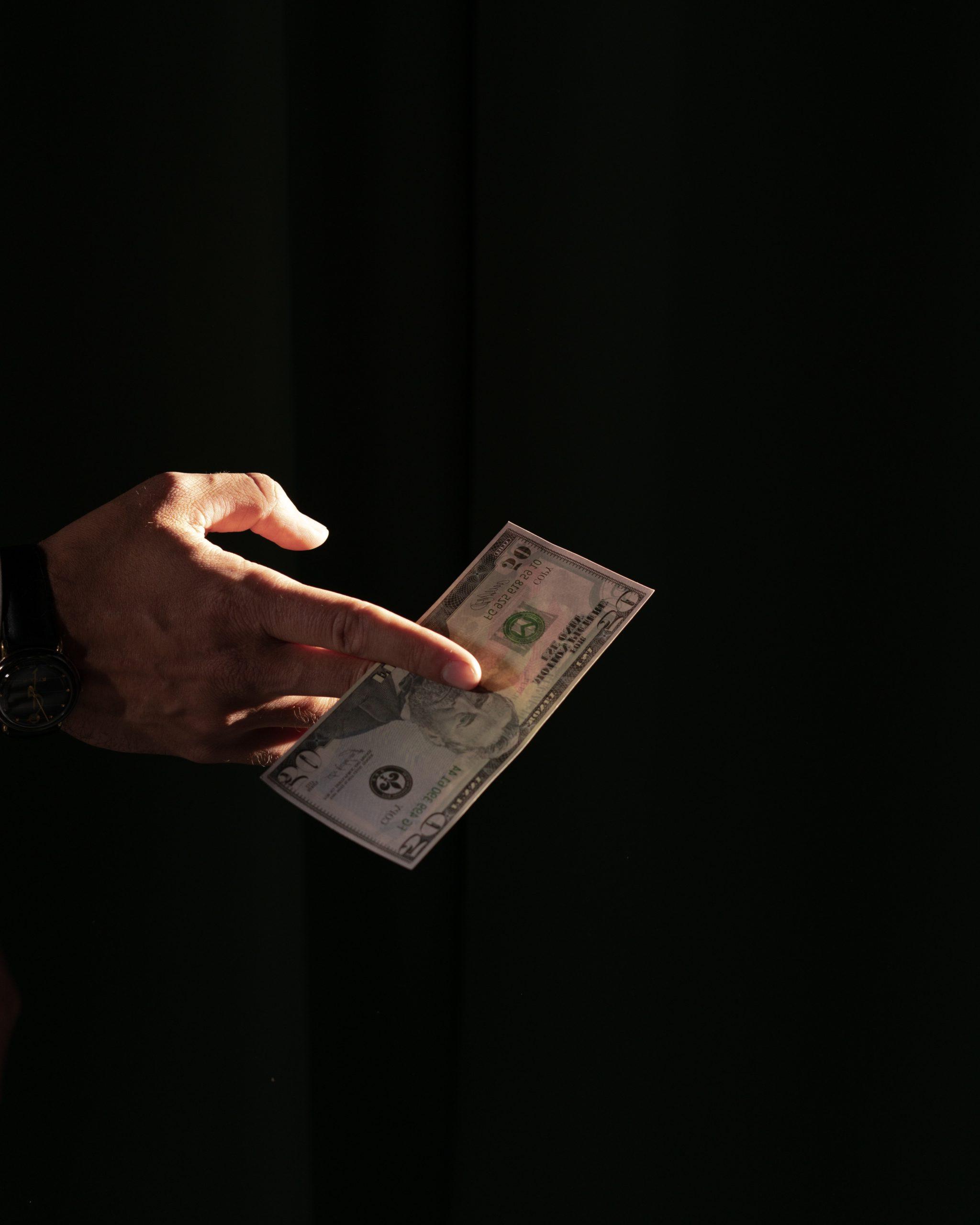 A hand presenting a $50 bill between fingers