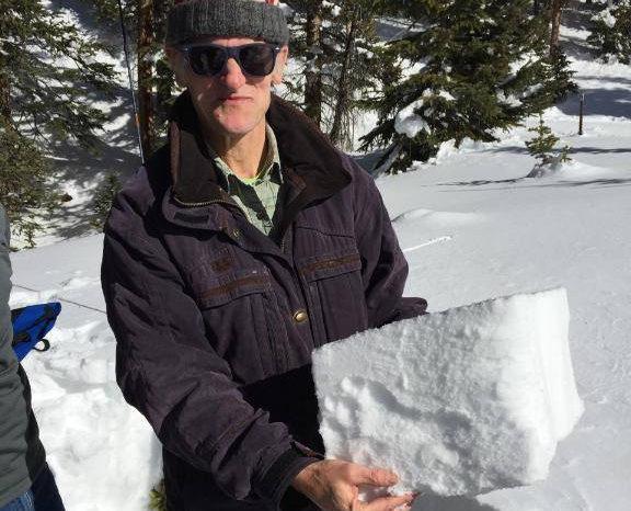 Dr. Rich Wagner holding a freshly cut snow block in the forest