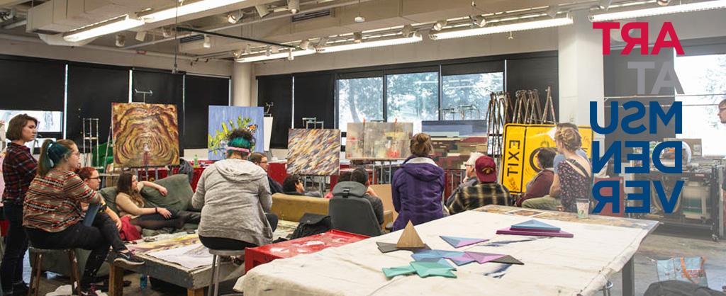 Students sitting in front of canvases covered in paint