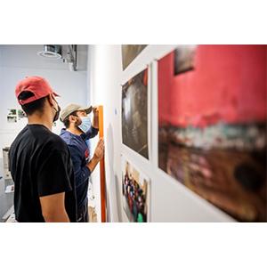 Students, wearing face masks, looking at art on wall