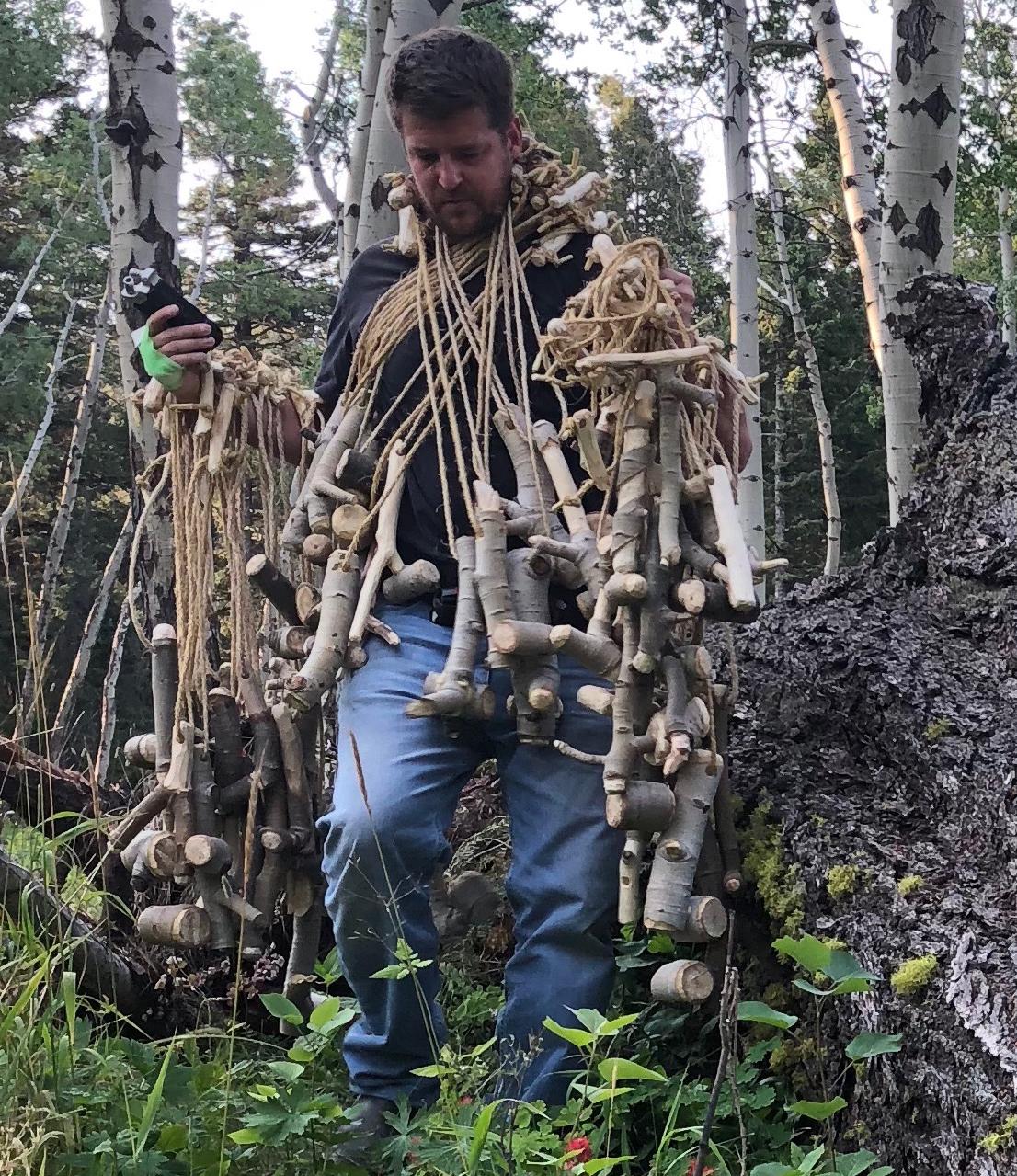 Professor Marin Abell surrounded by wooden sculpture almost looking like he is wearing it as a costume.