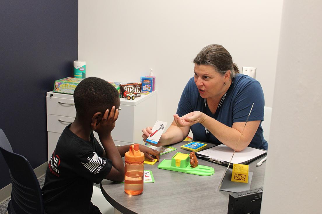 Graduate MS SLP student (left) working with elementary school aged child (right)