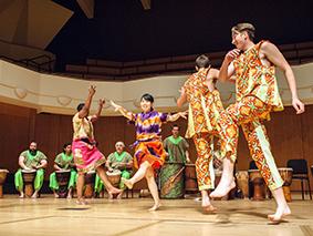 Dancers in traditional African dress performing in front of drummers