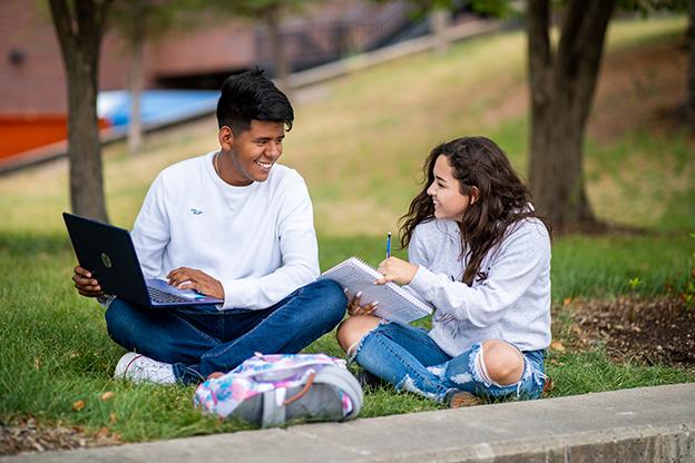 Two students sitting outside on campus studying