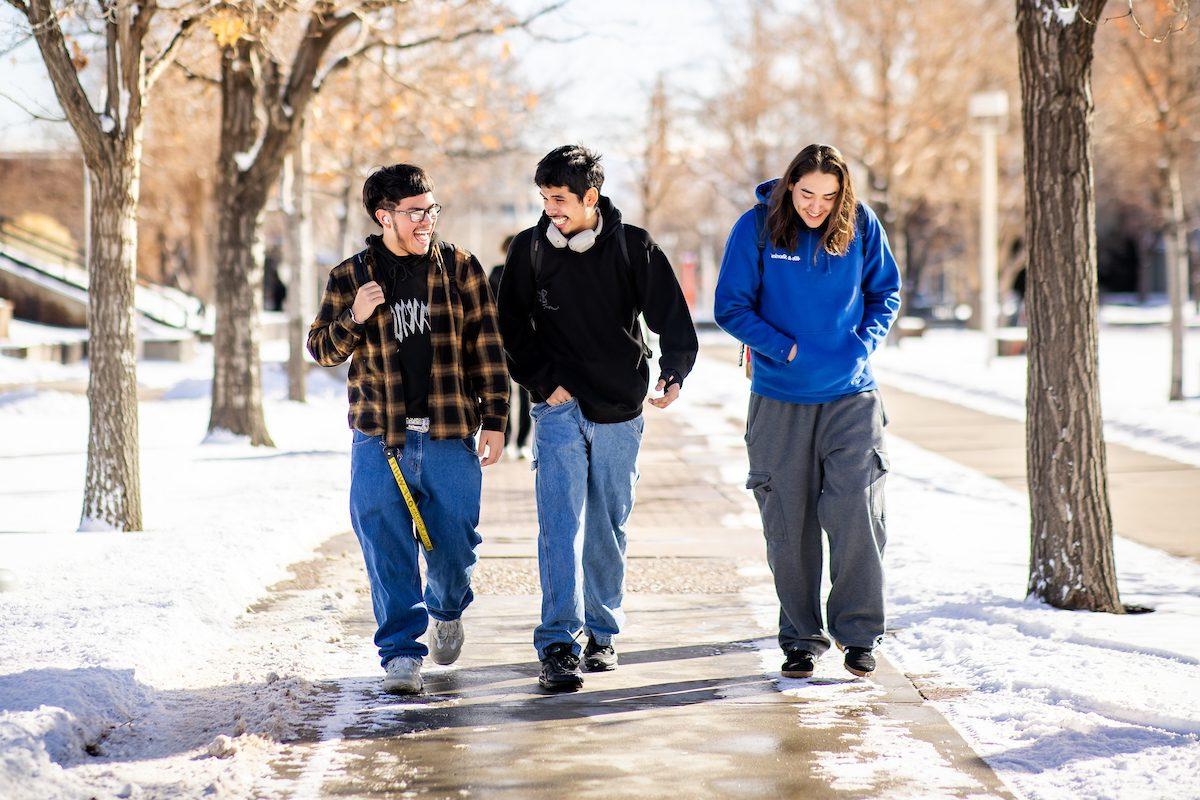 Three students walking on campus in the snow