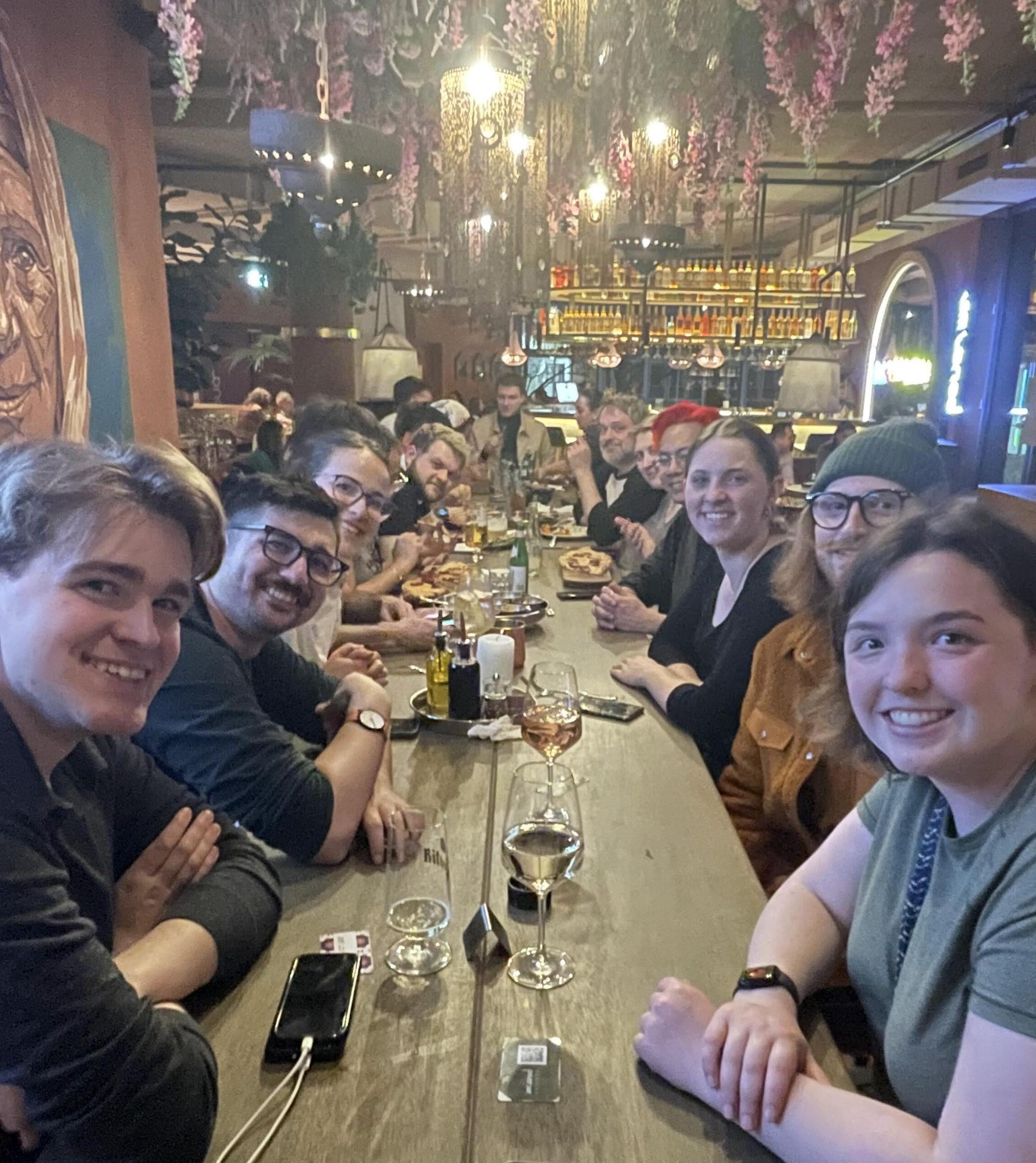 Several students sitting at very long restaurant table smiling at camera