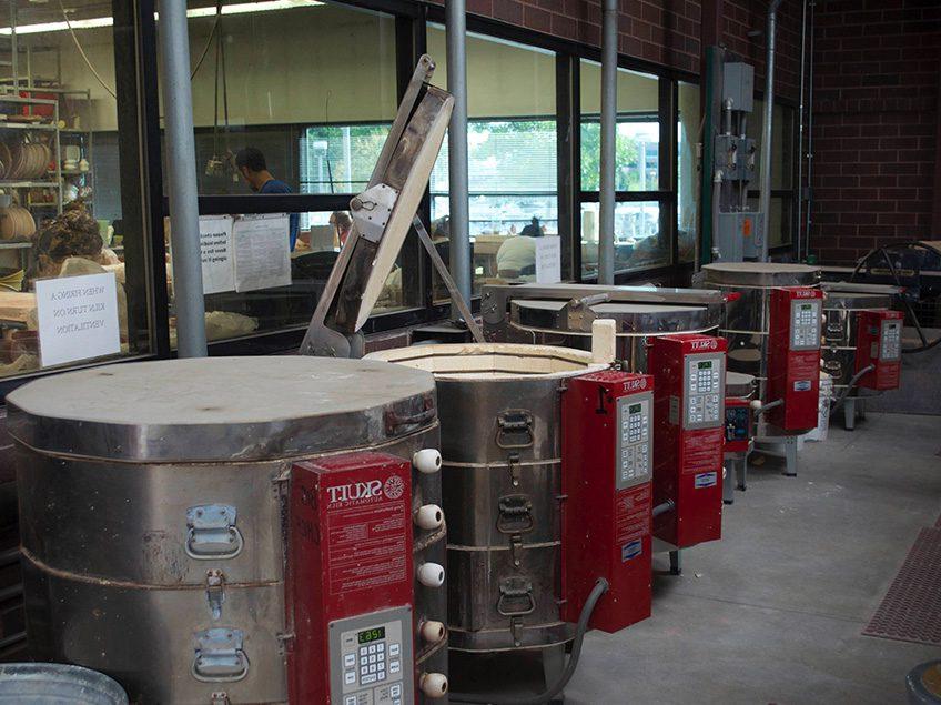 Photograph of 7 electric kilns in a row in the kiln yard at MSU Denver Department of Art ceramics studio.