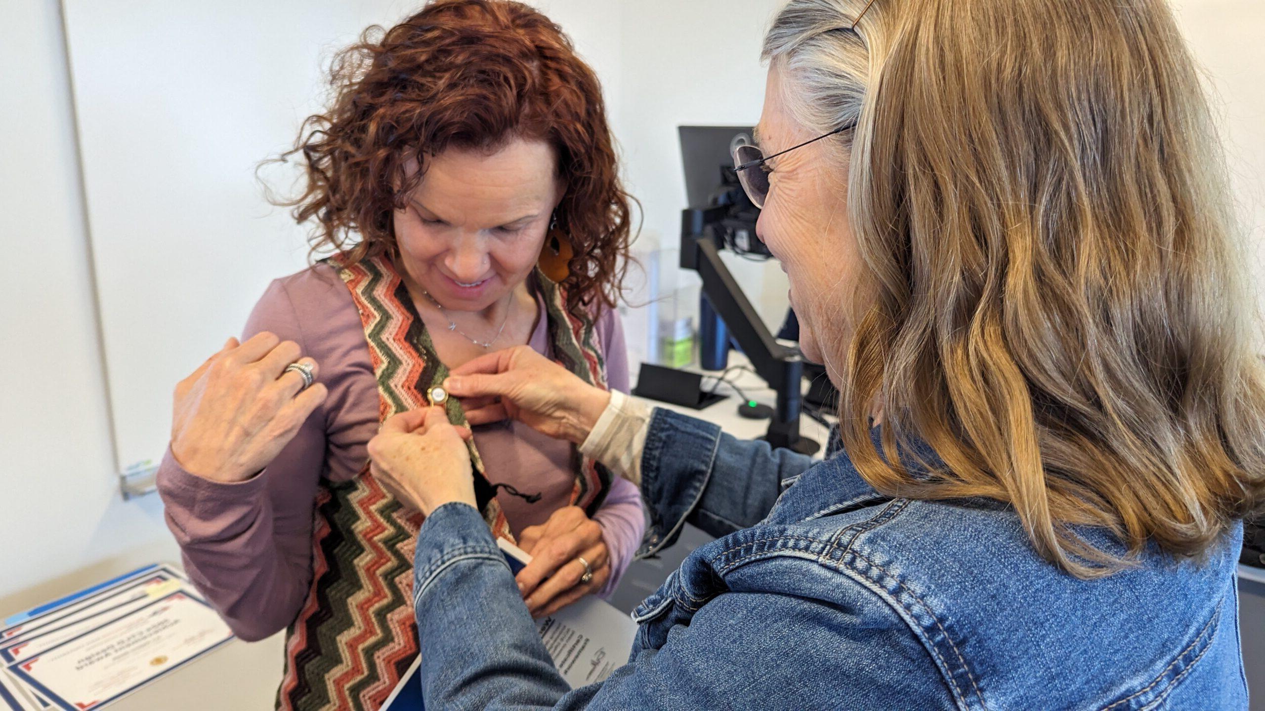 Chair pinning ACUE pin on faculty member who completed ACUE courses