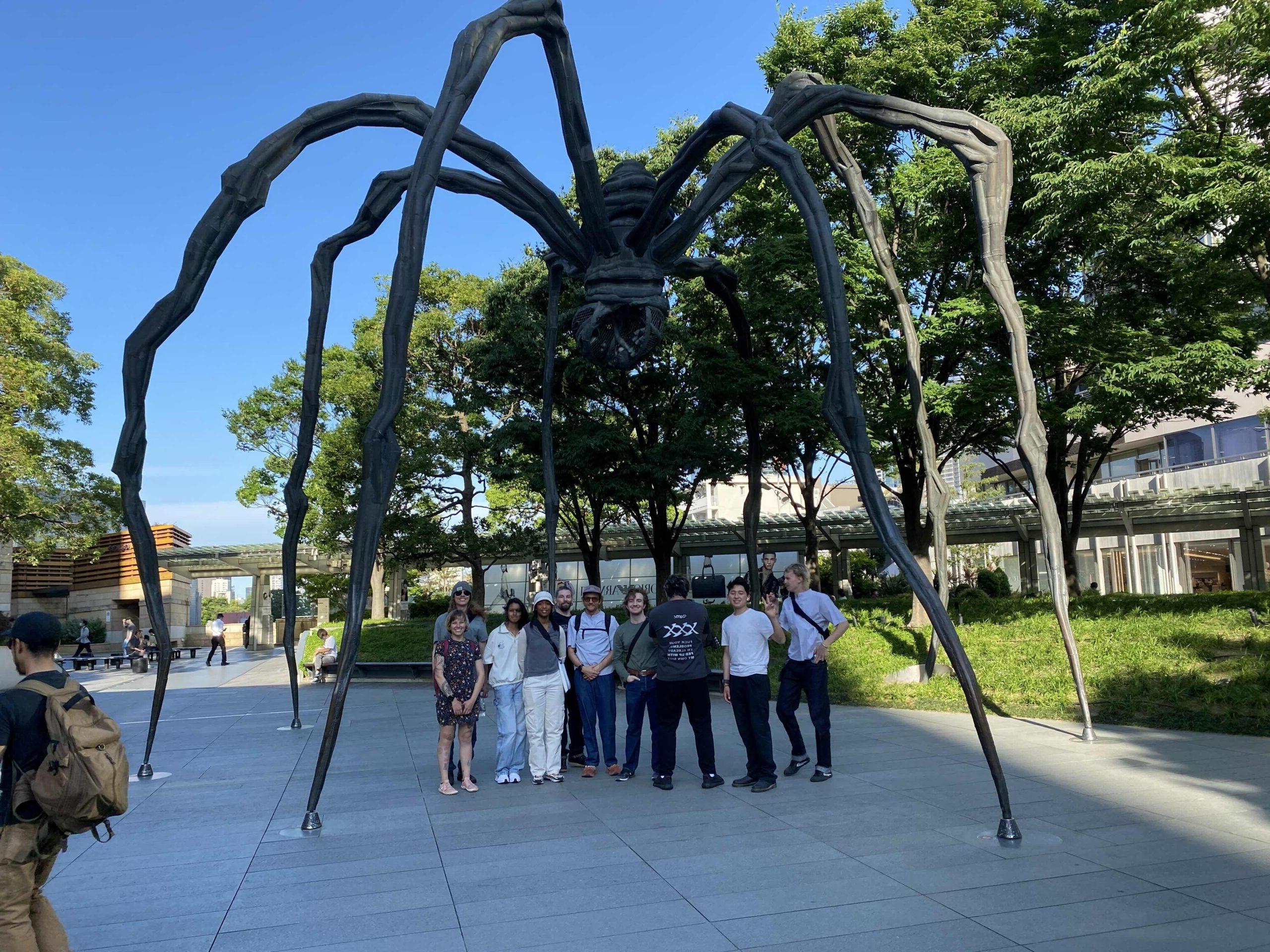 Art piece of giant spider with students standing underneath it