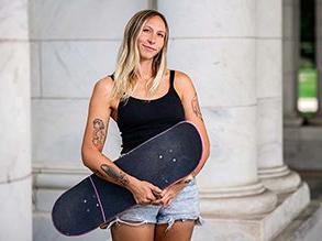 Mary Sullivan stands holding a skateboard.