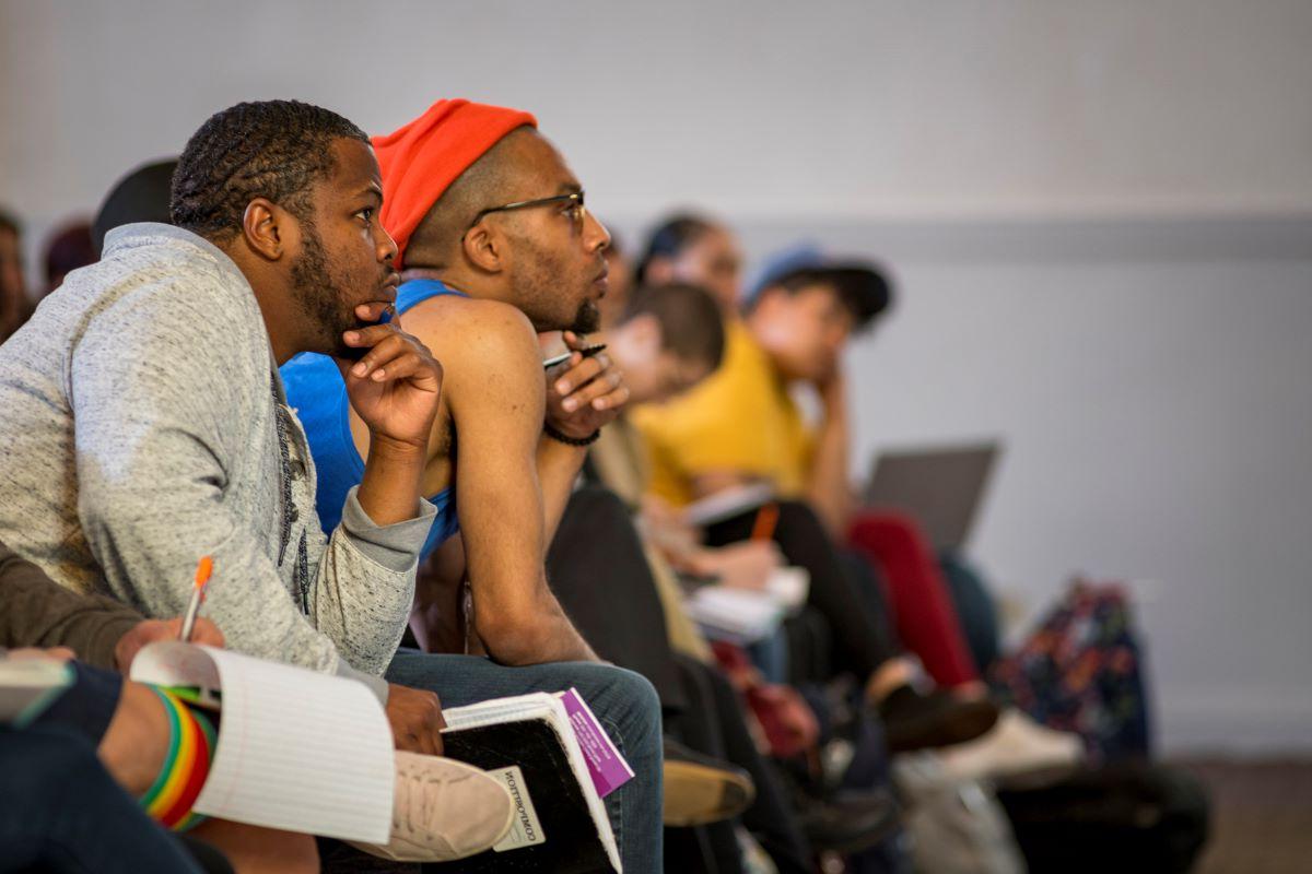 Two students sit with their hands holding pencils on their chin